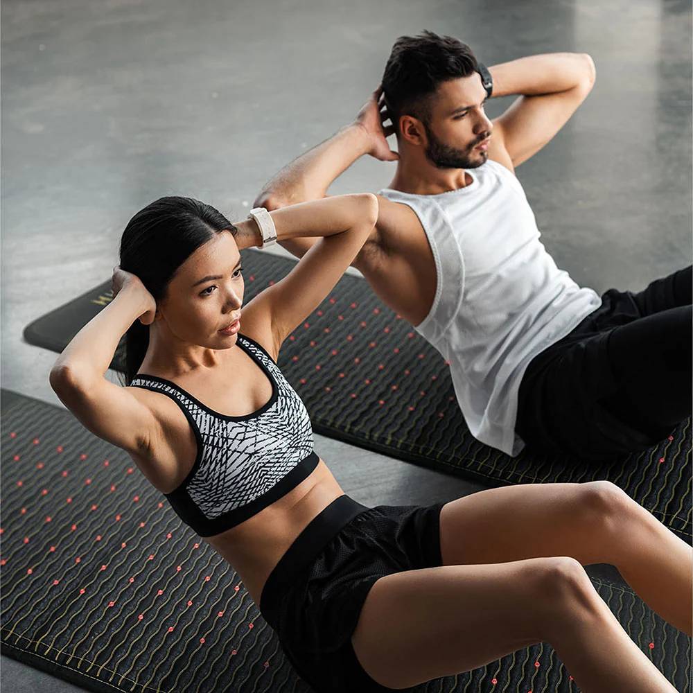 Couple Exercising – A man and woman do sit-ups on Jet infrared heating mats
