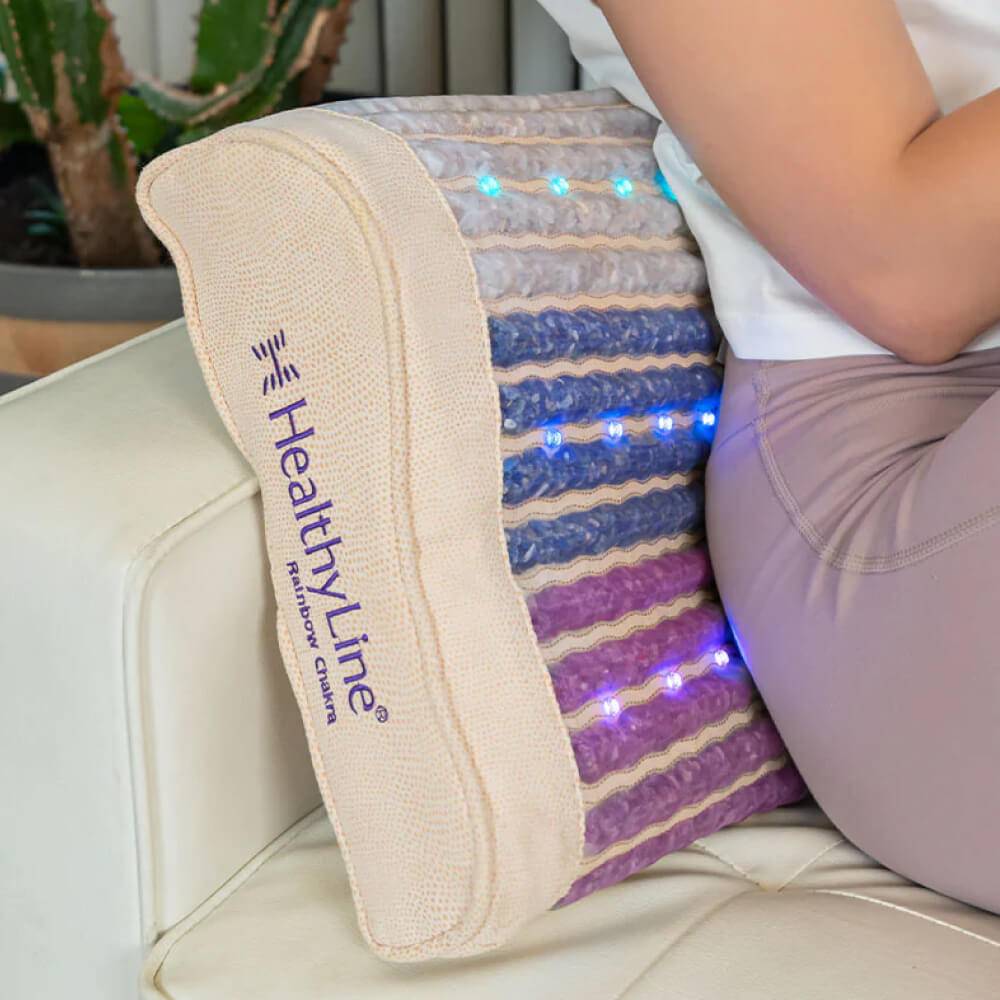 Close-up of Rainbow Chakra Heated Pillow used as a backrest with glowing LEDs