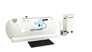 An OXYAIR hyperbaric chamber in white with a black rectangular mat on a clean white studio background.