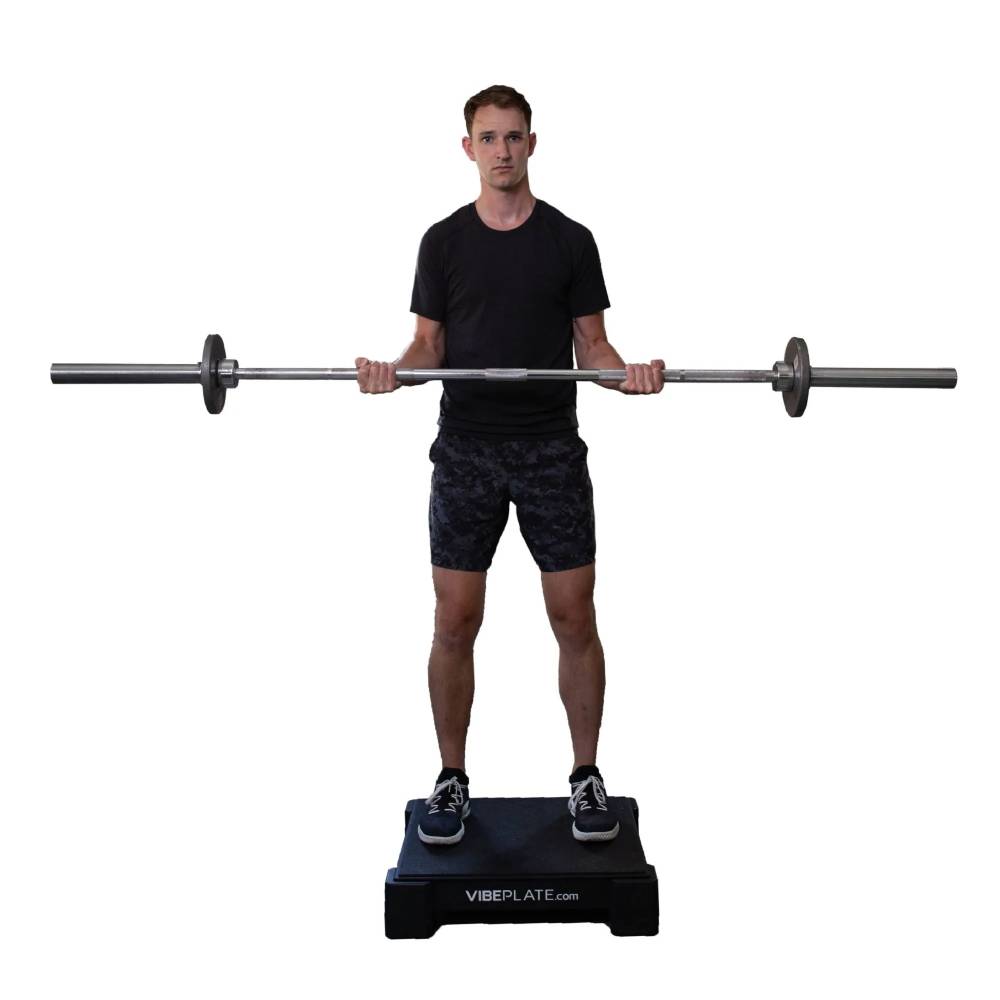 User performing a barbell curl exercise on the VibePlate 2424 vibration platform