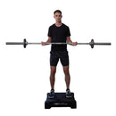 User performing a barbell curl exercise on the VibePlate 2424 vibration platform