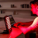 BestQool BQ40 red light therapy panel in use on a desk beside a laptop