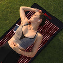 Woman relaxing on the BioMol red light therapy mat outdoors