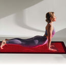 Woman doing a cobra yoga pose on the glowing BioMol red light therapy mat