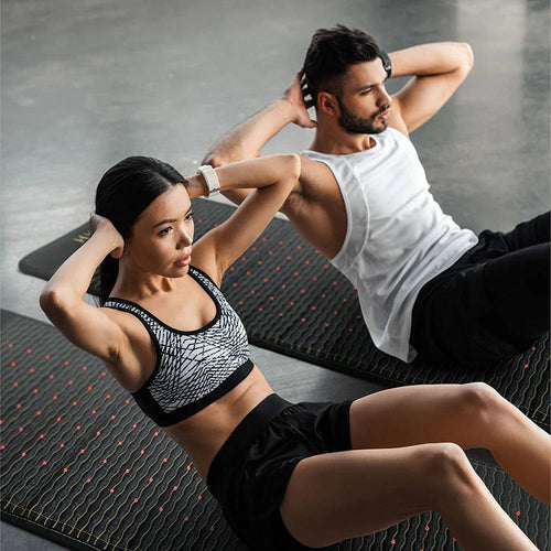 Couple Exercising – A man and woman do sit-ups on Jet infrared heating mats