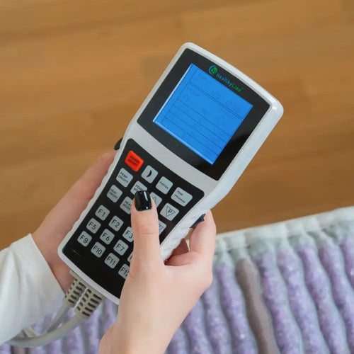 Hand holding the HealthyLine Platinum advanced PEMF controller above the mat