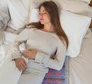 Woman resting on a bed with a HealthyLine Platinum PEMF mat lit beneath her