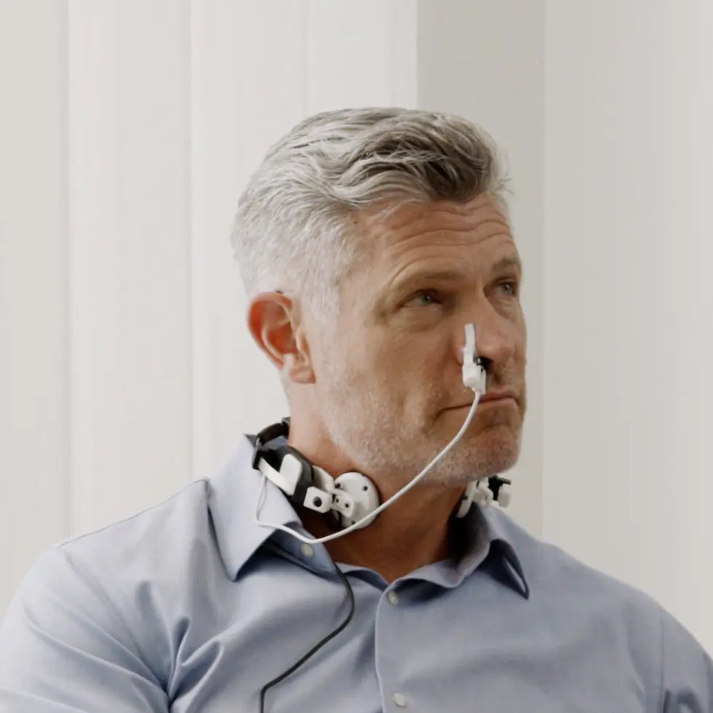A middle-aged man wearing the Vielight Vagus device, demonstrating the proper placement of the neck collar and the intranasal light therapy clip.